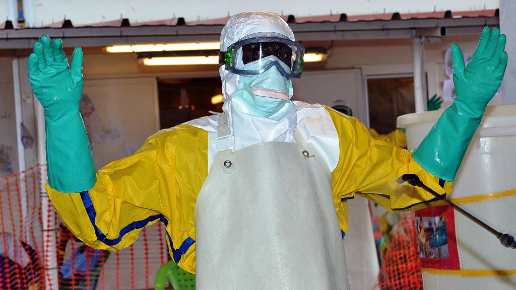 A health worker wearing protective gear is sprayed with disinfectant at the Nongo ebola treatment centre in Conakry, Guinea