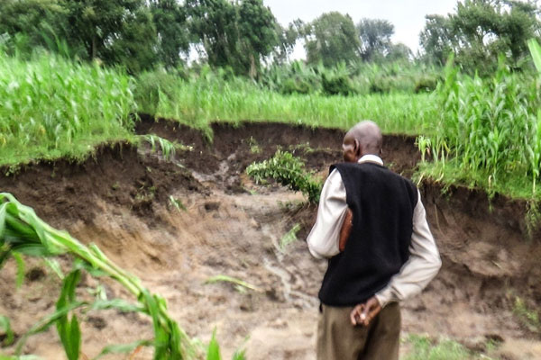 A man stands near a landslide scene in Nabukelema Cell