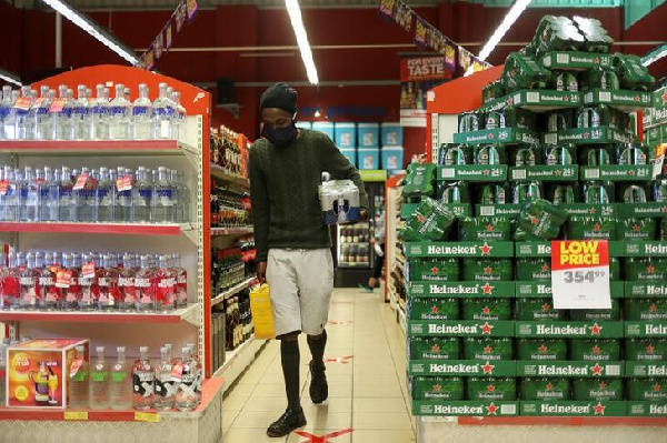 A man wearing a protective face mask buys alcohol at a liquor store