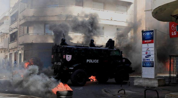 A security forces vehicle drive past burning tyres in capital, Dakar