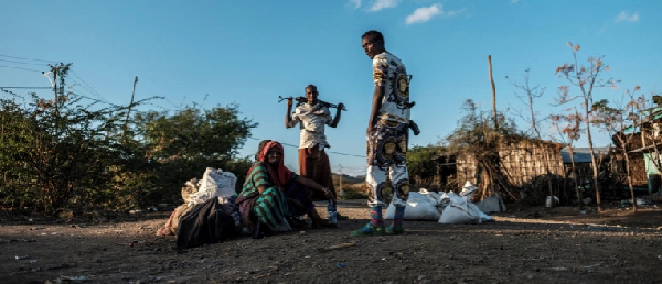 Men holding weapons stand next to a woman in the village of Bisober, in Ethiopia's Tigray region