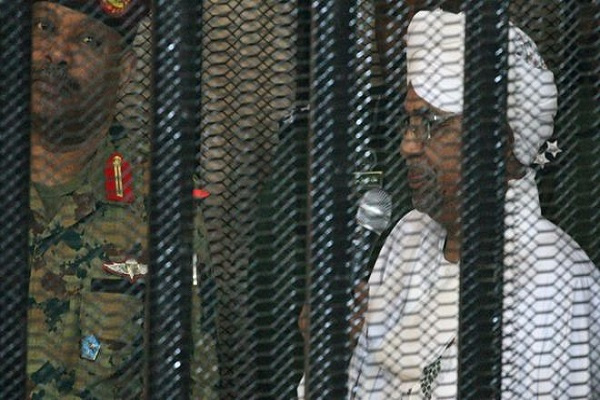 Omar al-Bashir appearing in court in a cage
