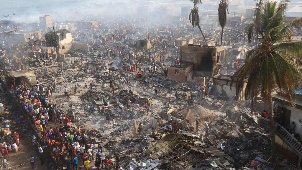 People look on at the aftermath of a large fire that broke out in an informal settlement in Susan’s Bay, Freetown on March 25, 2021