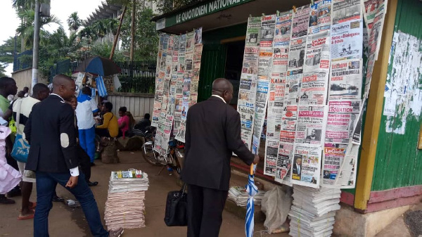 Some Cameroonians reading newspaper front pages at a kiosk adjacent the Ministry of Finance in Yaoun