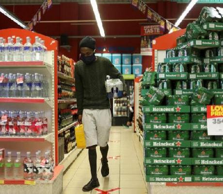 A man wearing a protective face mask buys alcohol at a liquor store