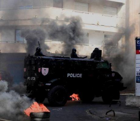 A security forces vehicle drive past burning tyres in capital, Dakar