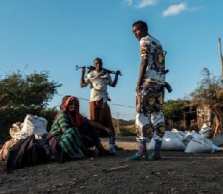 Men holding weapons stand next to a woman in the village of Bisober, in Ethiopia's Tigray region