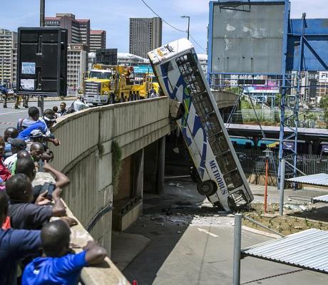 Onlookers gather on Queen Elizabeth bridge to look at a public transport bus that drove over the side of the bridge in Johannesburg, South Africa, on February 25, 2015