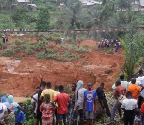 People watch an area affected by landslide after heavy rains that killed at least 13 people