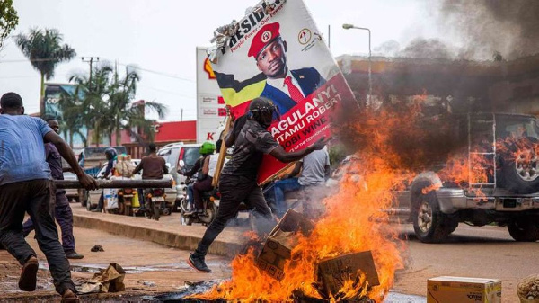 A supporter of Bobi Wine carries his poster as they protest against his arrest PHOTO | AFP