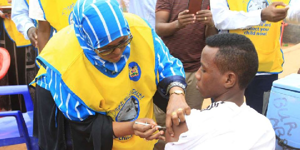 A woman administers the meningitis vaccine to a pupil