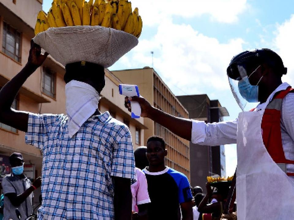 A Uganda Red Cross volunteer conducts a temperature check on a vendor in Kampala