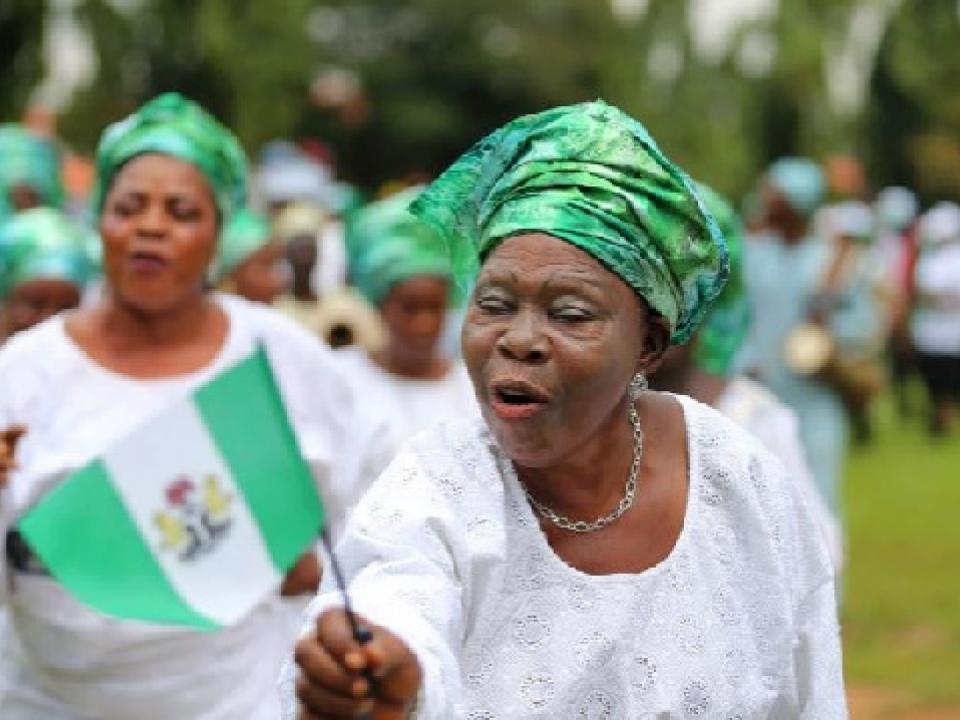 A woman raises the Nigerian flag as she participates in a parade to mark Nigeria's 55th anniversary