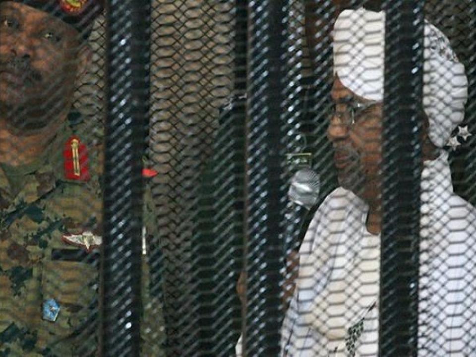 Omar al-Bashir appearing in court in a cage