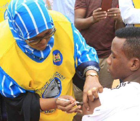 A woman administers the meningitis vaccine to a pupil