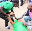 Men help a woman who fainted after police teargassed rioters in downtown Kampala